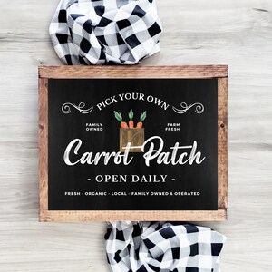 Op de afbeelding: Een zwart krijtbord met witte tekst die "Pick Your Own Family Owned Farm Fresh Carrot Patch - Open Daily - Fresh Organic Local Family Owned & Operated" luidt. Het bord heeft een tekening van een krat met wortels.