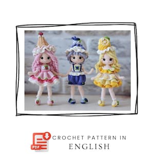 May include: Three handmade crochet dolls featuring fruit-themed outfits and hats. The left doll wears pink with strawberries, the center doll wears blue with blueberries, and the right doll wears yellow with lemon slices. Text reads: CROCHET PATTERN IN ENGLISH.