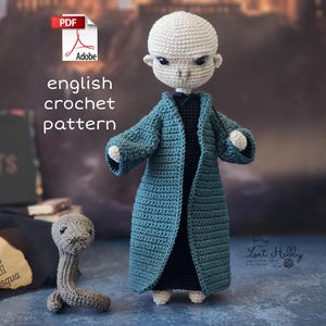 May include: Crochet pattern for a green-robed figure with a bald head and a snake. The pattern is written in English and is available as a PDF download. The text "english crochet pattern" is written in white on a black background.