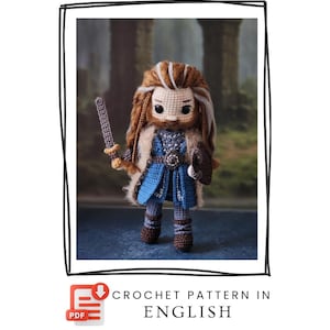 May include: A crocheted doll of a warrior, featuring a long, flowing brown and blonde beard and hair. The doll wears a blue tunic, a belt, and brown boots. It holds a sword and a shield. The text "CROCHET PATTERN IN ENGLISH" is visible.