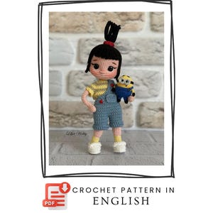 May include: A handmade crochet doll of a girl with black hair in a bun, wearing a yellow shirt and blue dungarees. She holds a small Minion doll. The doll is standing on a grey surface. The image includes the text "CROCHET PATTERN IN ENGLISH".