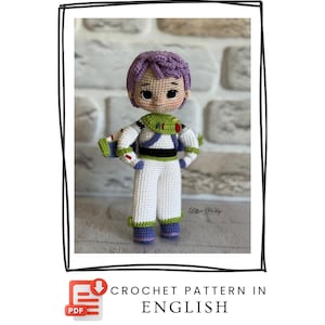 Puede incluir: Muñeco de ganchillo de un personaje de guardabosques espacial, con pelo morado, un traje espacial blanco con detalles verdes y negros, y un bláster. El muñeco está hecho a mano y está de pie. Incluye el texto "CROCHET PATTERN IN ENGLISH".