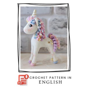 May include: A handmade white crochet unicorn with a colorful mane and tail. The unicorn has a golden horn, star accents, and is adorned with pastel-colored yarn and beads. The image includes the text "CROCHET PATTERN IN ENGLISH".