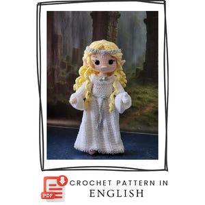 Puede incluir: Muñeca de ganchillo hecha a mano de una hada con cabello amarillo, vestida con un vestido blanco y una diadema plateada. La muñeca tiene orejas puntiagudas. El texto "CROCHET PATTERN IN ENGLISH" es visible.