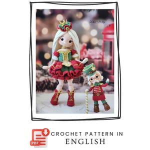 Könnte beinhalten: Ein Häkelmuster auf Englisch mit zwei Puppen zum Thema Weihnachten. Eine Puppe ist ein Mädchen mit Krone, langem weißem Haar und einem roten, grünen und goldenen Kleid. Die andere Puppe ist ein Nussknacker in roter Uniform und grüner Mütze.