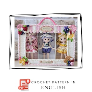 May include: A crochet display case featuring three dolls with pink, purple, and yellow hair, decorated with yarn strawberries, blueberries, and citrus slices. The case has a handle and labels reading Ice Cream and Sweet Scoops Collection.