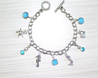 Ladies' chain link charm bracelet with beach theme charms, spacers and toggle closure.