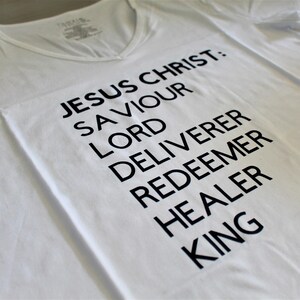 Ladies 100% cotton short-sleeved t-shirt with &quot;Jesus Christ: Savior, Lord, Redeemer, Deliverer, Healer, King&quot; wording.