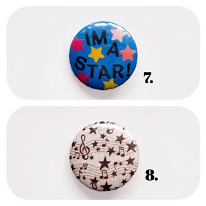 以下が含まれることがあります： 2つの丸いピンバッジ。1つ目は「I'M A STAR！」の文字とピンクと黄色の星のグラフィックが入った青色。2つ目は、音符と星のグラフィックが入ったタン色です。