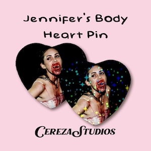 May include: A pink background features two heart-shaped images of a woman with vampire fangs and blood. The text "Jennifer's Body Heart Pin" is above the hearts, and "Cereza Studios" is below.
