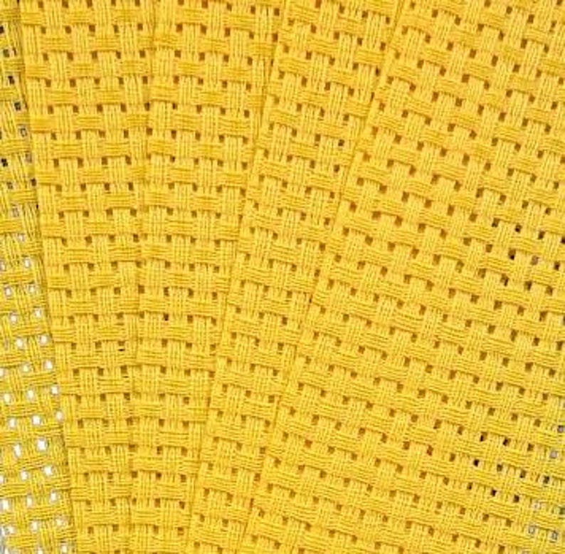 May include: A bright yellow fabric featuring a distinct basketweave texture. The material displays a consistent grid pattern created by interlacing thick, horizontal and vertical threads, resulting in a dense, uniform, and structured textile surface.