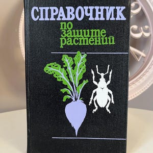 May include: A black book with the title "СПРАВОЧНИК по защите растений" in white text. The cover features a green plant with a purple root and a white beetle.
