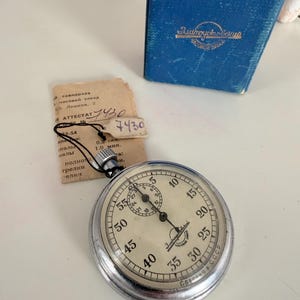 Può includere: Una tazza di ceramica bianca con manico nero e la scritta "But First, Coffee" in nero, con un carattere a mano. La tazza è su una superficie bianca.