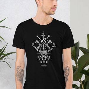 Puede incluir: Una camiseta negra con un diseño geométrico blanco. El diseño presenta un patrón similar a un copo de nieve con una forma de media luna en la parte superior.