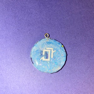 May include: A round blue resin pendant with silver glitter and a white letter "J" inside.