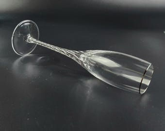 May include: A clear glass champagne flute with a twisted stem and a thin gold band around the rim.
