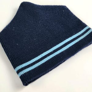 Pode incluir: Um gorro de malha azul marinho com duas listras azuis claras.