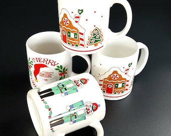 May include: Four white ceramic mugs with Christmas-themed designs. One mug features a gingerbread house, another has a Christmas tree, a third has a Santa Claus, and the last one has a Nutcracker.