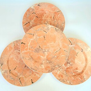 Puede incluir: Juego de cuatro platos redondos de cerámica con un patrón de mármol rosa y blanco.