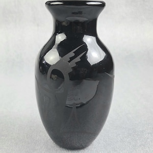 Peut inclure: Un vase noir brillant avec un col fin et un corps arrondi. Le vase présente un motif gravé d'un oiseau en vol. Le vase mesure environ 15 cm de haut, parfait pour exposer des fleurs ou comme élément décoratif.