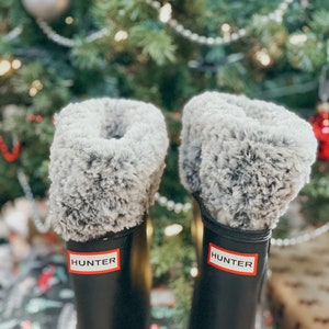 May include: A pair of black Hunter rain boots with gray faux fur lining. The boots have the Hunter logo on the side.