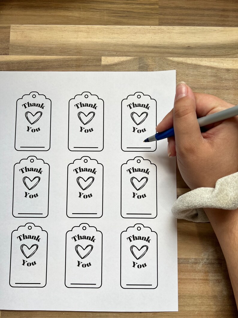 May include: Printable sheet of nine gift tags with a black outline. Each tag has a heart with the text "Thank You" above it.