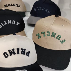 May include: A collection of baseball caps in various colors, including black, navy, and tan. Each cap features embroidered text in contrasting colors, such as white, green, and black. The caps have a classic six-panel design with a curved brim.