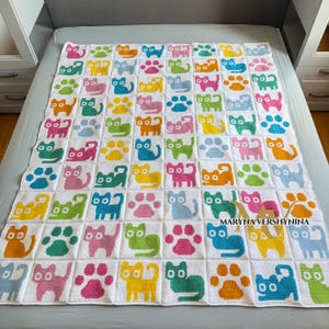 K&ouml;nnte beinhalten: Eine wei&szlig;e H&auml;keldecke mit einem sich wiederholenden Gittermuster aus bunten Katzensilhouetten und Pfotenabdr&uuml;cken in Rosa, Blau, Gr&uuml;n, Gelb und Orange. Der Text MARYNA VERSHYNINA ist in Schwarz auf der unteren rechten Seite aufgedruckt.