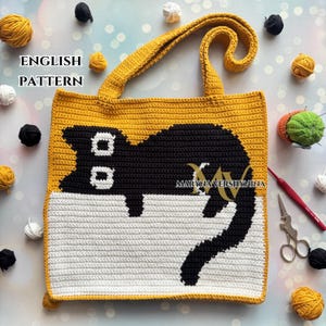 May include: A crocheted tote bag with a black cat design. The bag is yellow with a white stripe and black cat silhouette. The bag has a yellow handle.