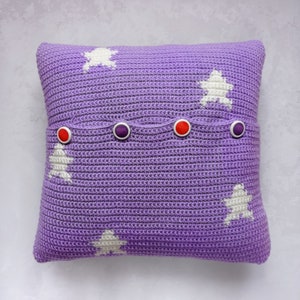 May include: Purple crocheted pillow with white star designs and red and purple buttons.