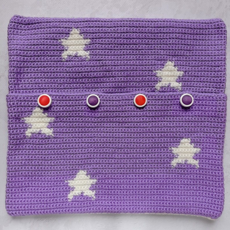 May include: Purple crocheted pouch with white star designs and red and purple buttons.