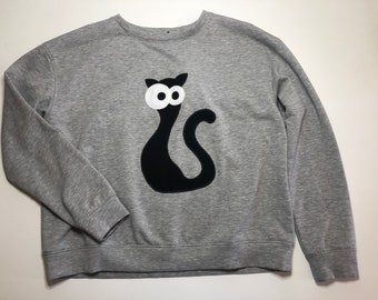 May include: A gray sweatshirt with a black cat appliqué with white eyes. The cat is sitting on its haunches with its tail curled around its body.