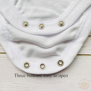 May include: Close-up of a white baby bodysuit with three popper fastenings. The text "Three buttons, easy to open" is printed at the bottom. The bodysuit is made of soft, white fabric.