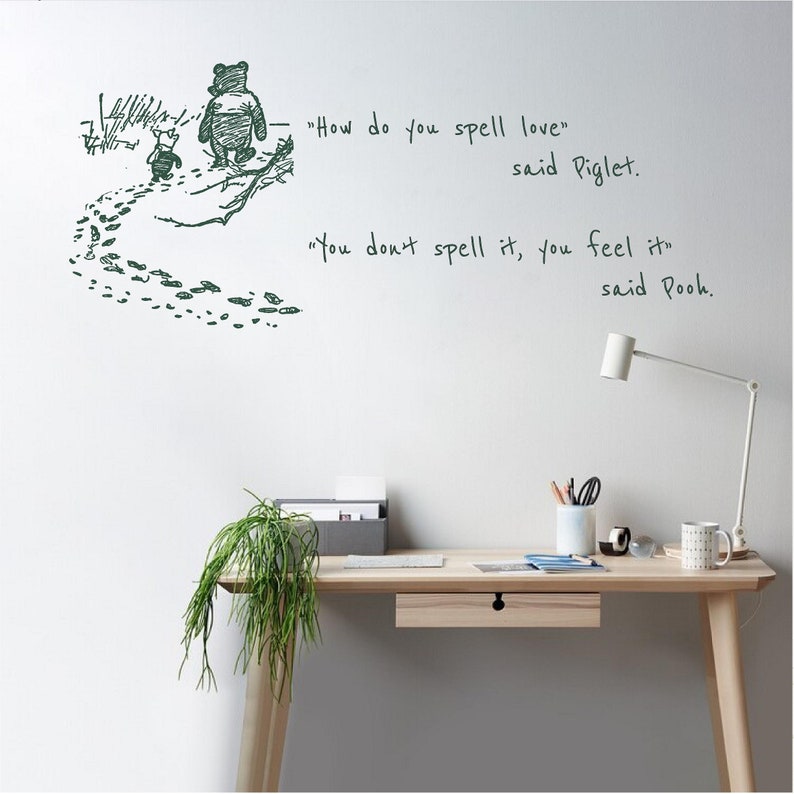 Puede incluir: Una cita de Winnie de Pooh sobre el amor, "&iquest;C&oacute;mo se escribe amor?" dijo Piglet. "No se escribe, se siente" dijo Pooh. La cita est&aacute; escrita en tinta negra sobre una pared blanca con un dibujo de Winnie de Pooh y Piglet caminando por el bosque.