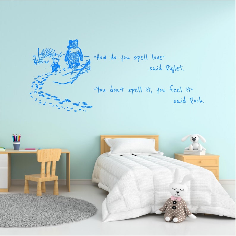 Puede incluir: Una calcoman&iacute;a de pared azul de Winnie the Pooh con una cita de Pooh y Piglet caminando por el bosque. La cita dice "&iquest;C&oacute;mo se deletrea amor?" dijo Piglet. "No se deletrea, se siente" dijo Pooh.
