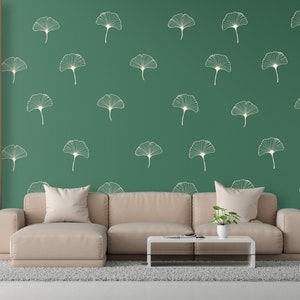 Puede incluir: Una sala de estar con un sofá seccional marrón claro, una mesa de café y una lámpara de pie. La pared está pintada de un color verde oscuro y presenta un patrón repetitivo de hojas de ginkgo blancas.