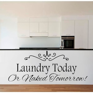 Könnte beinhalten: Eine weiße Küchenarbeitsplatte mit einer schwarzen Arbeitsplatte. Ein schwarzer und weißer Vinyl-Aufkleber mit der Aufschrift "Laundry Today Or Naked Tomorrow!" mit einer dekorativen Verzierung über dem Text.