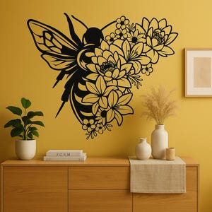 May include: Black bee and floral wall art. The design features a bee with detailed wings and a body, combined with various flower types. The artwork is mounted on a yellow wall, creating a striking contrast. The bee is surrounded by flowers.