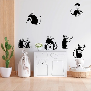 May include: Black silhouette wall decals of rats in various poses, including one with a drill, another with a parachute, and others playing instruments. The decals are applied to a white wall above a white chest of drawers and near a cactus.