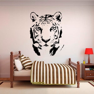 May include: Black and white silhouette of a tiger's face, a wall decal, above a striped bedspread on a twin-sized bed.