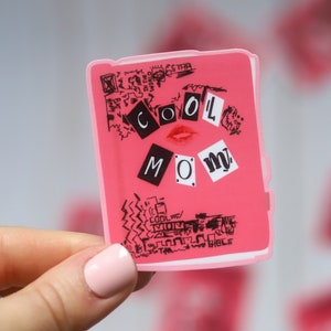 May include: A pink sticker with black lettering that reads "COOL MOM" with a red lipstick kiss mark. The sticker has a black and white doodle design around the lettering.