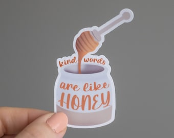 May include: A white sticker with a honey pot and a honey dipper pouring honey into the pot. The text on the sticker reads "kind words are like honey".