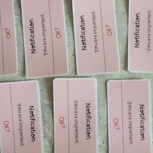 May include: Six pink paper notes with the text "Notification you are important. OK?" printed on them.