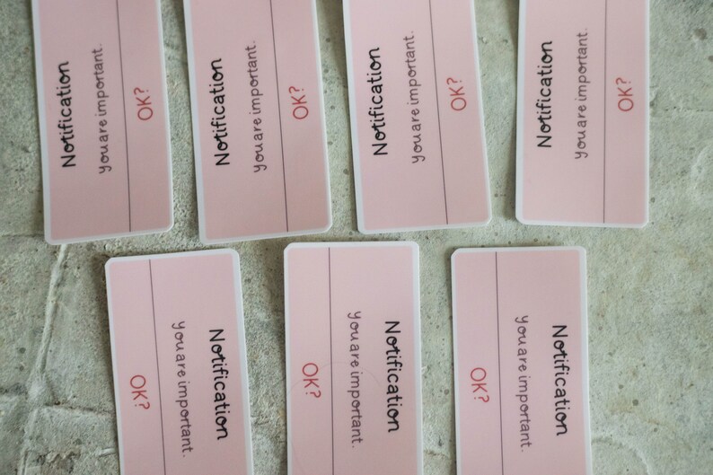 May include: Six pink paper notes with the text "Notification you are important. OK?" printed on them.