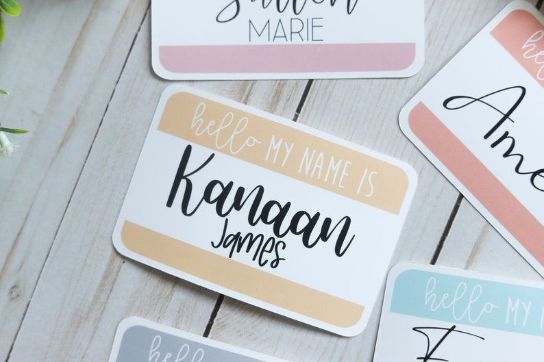 May include: A white name tag with a peach colored stripe. The text on the tag reads "hello my name is Kanaan James".