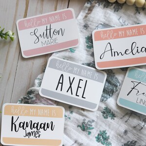 May include: Five colorful name tags with the text "hello my name is" followed by a name. The names are Sutton Marie, Amelia, Axel, Kanaan James, and Francisco Lincoln.