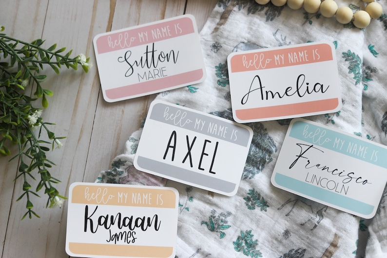 May include: Five colorful name tags with the text "hello my name is" followed by a name. The names are Sutton Marie, Amelia, Axel, Kanaan James, and Francisco Lincoln.