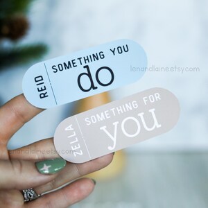 May include: Two stickers with a light blue and a light brown background. The blue sticker says "Reid" and "Something You Do" in black text. The brown sticker says "Zella" and "Something For You" in white text.
