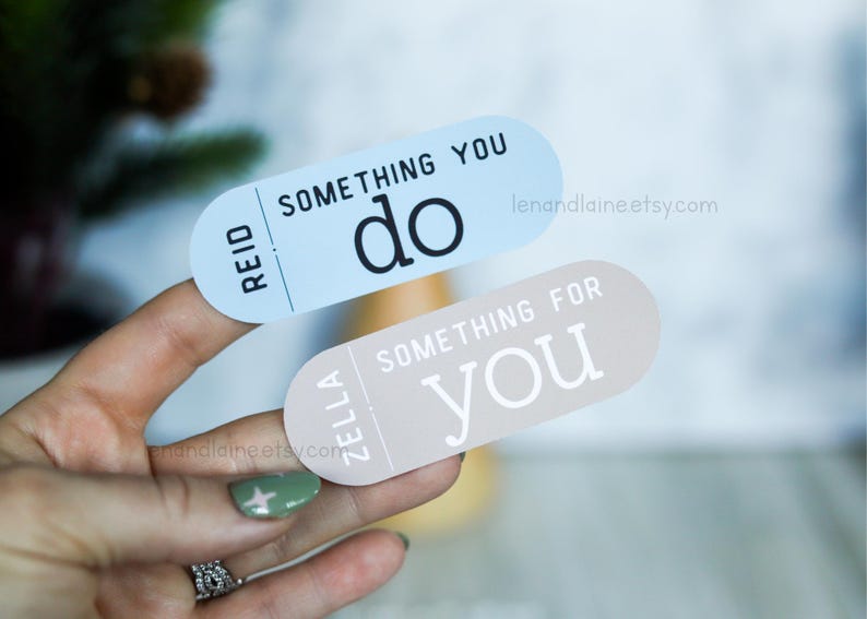 May include: Two stickers with a light blue and a light brown background. The blue sticker says "Reid" and "Something You Do" in black text. The brown sticker says "Zella" and "Something For You" in white text.