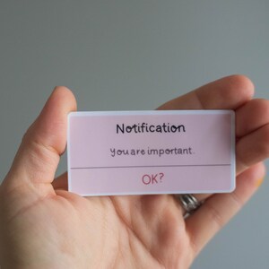 May include: A pink notification card with white text that reads "Notification" and "You are important."  The card also has the text "OK?" in red.